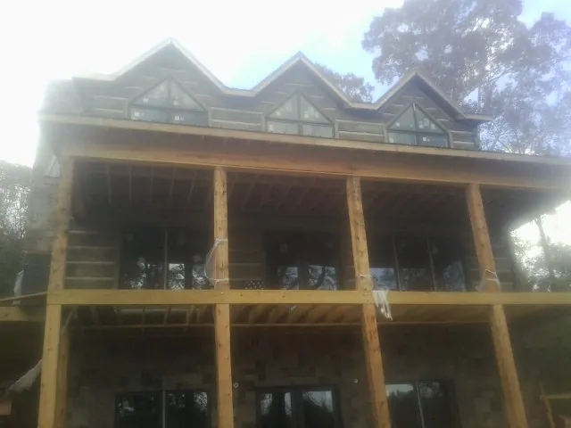 Dormers and porch framing on a large log home under construction — Roof Coating work by our crew in Manchester